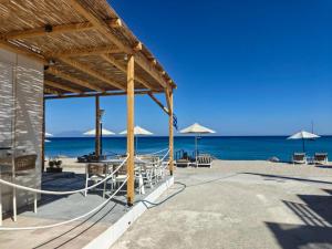 a pavilion on the beach with chairs and umbrellas at Aeolia Seaside Hotel in Kardamaina