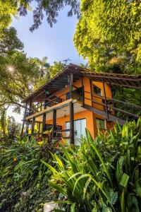 an orange house on a hill with trees and bushes at Pousada Lagamar in Praia Vermelha