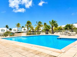a swimming pool with palm trees in the background at Studio Coconut in Baie Nettle