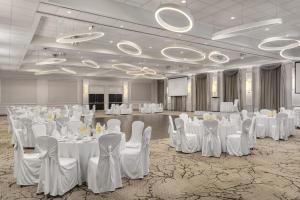 a banquet hall with white tables and chairs and a screen at Crowne Plaza Kitchener-Waterloo by IHG in Kitchener