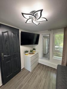 a living room with a flat screen tv and a door at Csillagkapu Vendégház in Kápolnásnyék