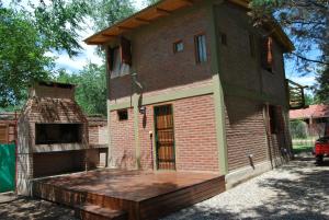 a large brick house with a large deck at TIERRA SERRANA CABAÑAS s in Villa Anizacate