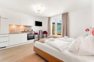 a bedroom with a large bed and a kitchen at Lake Lodge Ossiacher See in Annenheim