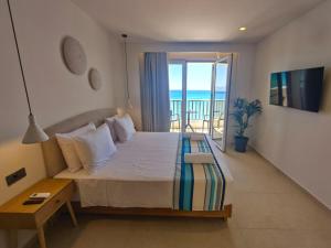 a bedroom with a bed with a view of the ocean at Aeolia Seaside Hotel in Kardamaina