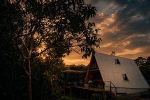 a house with a white roof and a tree at Chalé Canto do Rio - Vale do Capão in Palmeiras
