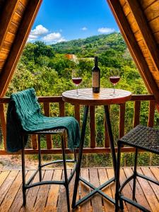 a table with two glasses of wine on a deck at Chalé Canto do Rio - Vale do Capão in Palmeiras