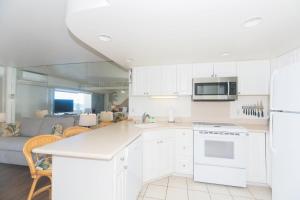 a kitchen with white cabinets and a living room at Ilikai Tower 633 in Honolulu