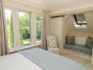a bedroom with a bed and a chair and windows at The Barn at Frog Pond Farm in Salisbury