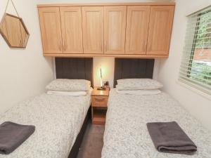 due letti in una piccola stanza con un armadio di legno di Willows Lodge a Windermere