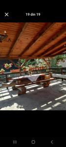 a picnic table under a wooden roof with flowers at Vila Mihnea in Moieciu de Jos