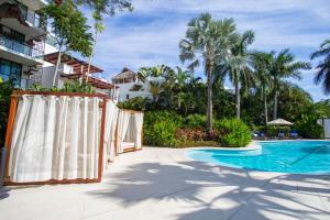 a pool at a resort with palm trees at Quiya Beach Residences in Cruz de Huanacaxtle