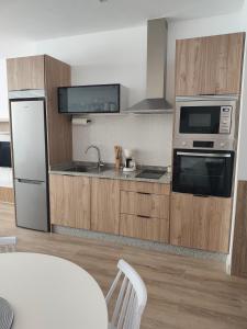 a kitchen with stainless steel appliances and wooden cabinets at apartamentos YEIK in Muxia