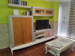 a living room with a tv and a entertainment center at Apartamento El Ferial in Sarón