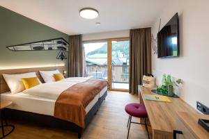 a hotel room with a large bed and a desk at JUFA Hotel Werfenweng in Werfenweng