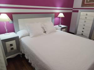 a bedroom with a white bed with purple walls at Apartamento El Ferial in Sarón