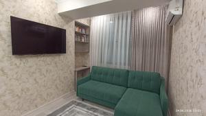 a living room with a green couch and a flat screen tv at Osh apartment in Osh