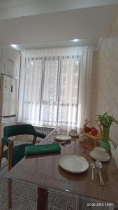 a dining room table with plates on it next to a window at Osh apartment in Osh +8 photos