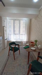 a living room with a table and chairs and a kitchen at Osh apartment in Osh