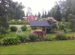 ein Garten mit einem Pavillon und einem roten Haus in der Unterkunft Tyynelä in Juupajoki