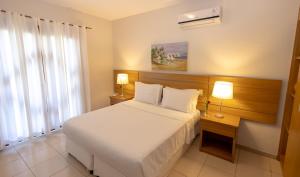 a bedroom with a bed and a desk with two lamps at Vitoria Regia Praia Hotel in Porto Seguro +72 photos