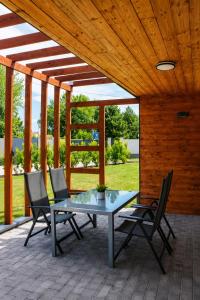 a table and chairs on a patio with a wooden ceiling at Fenyves Flow Apartman 1 in Balatonfenyves