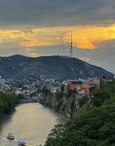 a river with a city and a tower on a hill at Garden Studio, Old Tbilisi in Tbilisi City