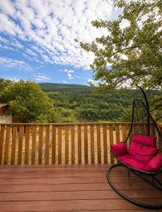 a chair sitting on a wooden deck with a view at Garden Cottages in Mestia