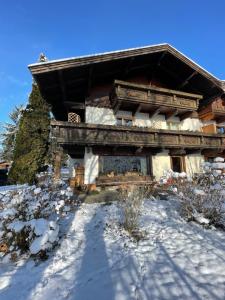 a building with snow on the ground in front of it at Haus am Bach in Erl