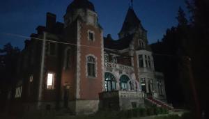 un antiguo edificio con una torre de reloj por la noche en Dofteana Park en Leorzeni