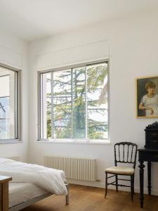 a bedroom with a bed and a chair and windows at Casa Navegna in Minusio