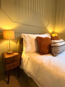 a bed with pillows and a lamp on a night stand at St Johns Central Canterbury Cottage in Canterbury