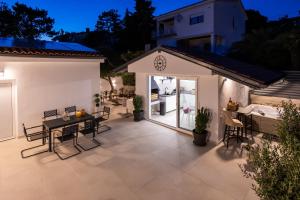 a patio with a table and chairs and a house at Korina Suites - 2 appartments, 1 with jacuzzy in Dramalj