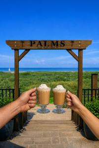 two people holding up two drinks on a wooden sign at Palms Resort & Cafe on the Beach in South Padre Island +35 photos