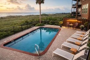 a swimming pool with chairs and the ocean in the background at Palms Resort & Cafe on the Beach in South Padre Island