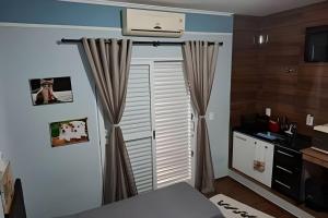 a room with a door with curtains and a kitchen at Tecnohouse próxima ao Sesc in Franca