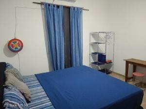 a bedroom with a bed with blue sheets and a window at L'Urbain in Ziguinchor