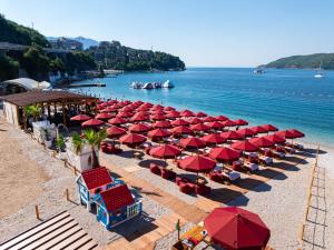 a bunch of red umbrellas and chairs on a beach at Hotel Imperial Conference & Spa in Budva