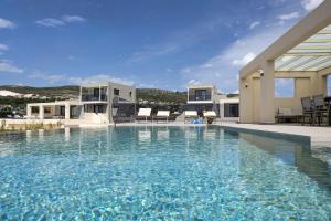 a large swimming pool with blue water in front of a house at TATOLI Villas in Minia
