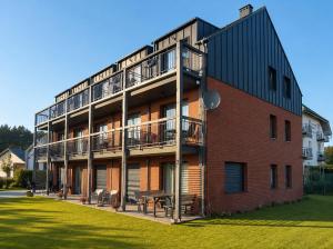 a brick building with a balcony and a picnic table at AMD Apartamenty Ustka *** in Ustka
