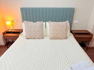 a large white bed with a blue headboard and pillows at Estudio en Villalonga in Pontevedra