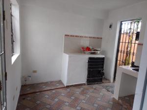 a kitchen with white walls and a brick floor at Bchome hostal in Boca Chica +3 photos