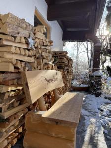 a pile of fire wood next to a wooden bench at Haus am Bach in Erl