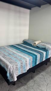 a bed with a striped comforter in a room at Mini flat 08 em Jataí Go in Jataí