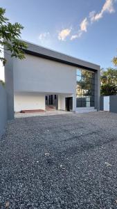 a white building with a black roof on a gravel driveway at Mini Flat 09 Jataí Go in Jataí