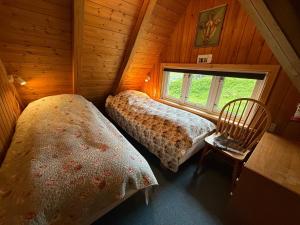 two beds in a room with a window at Unique and isolated cottage with stunning views in Leynar