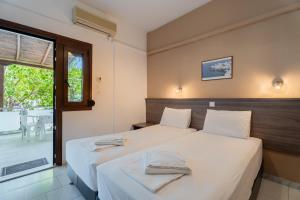 two beds in a room with a window at Studios Vaso in Neos Marmaras