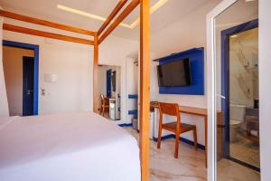 a bedroom with a bed and a desk and a tv at Vila Gallina Pousada in Jericoacoara