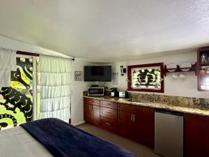 a bedroom with a bed and a kitchen with a television at Kalani Hawaii Private Lodging in Pupukea
