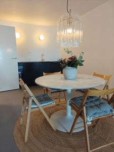 a dining room table with chairs and a vase on it at Sea view Ella - Hejlsminde Badehotel in Hejlsminde
