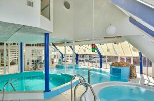 a large indoor swimming pool with a large blue swimming pool at Sea view Ella - Hejlsminde Badehotel in Hejlsminde